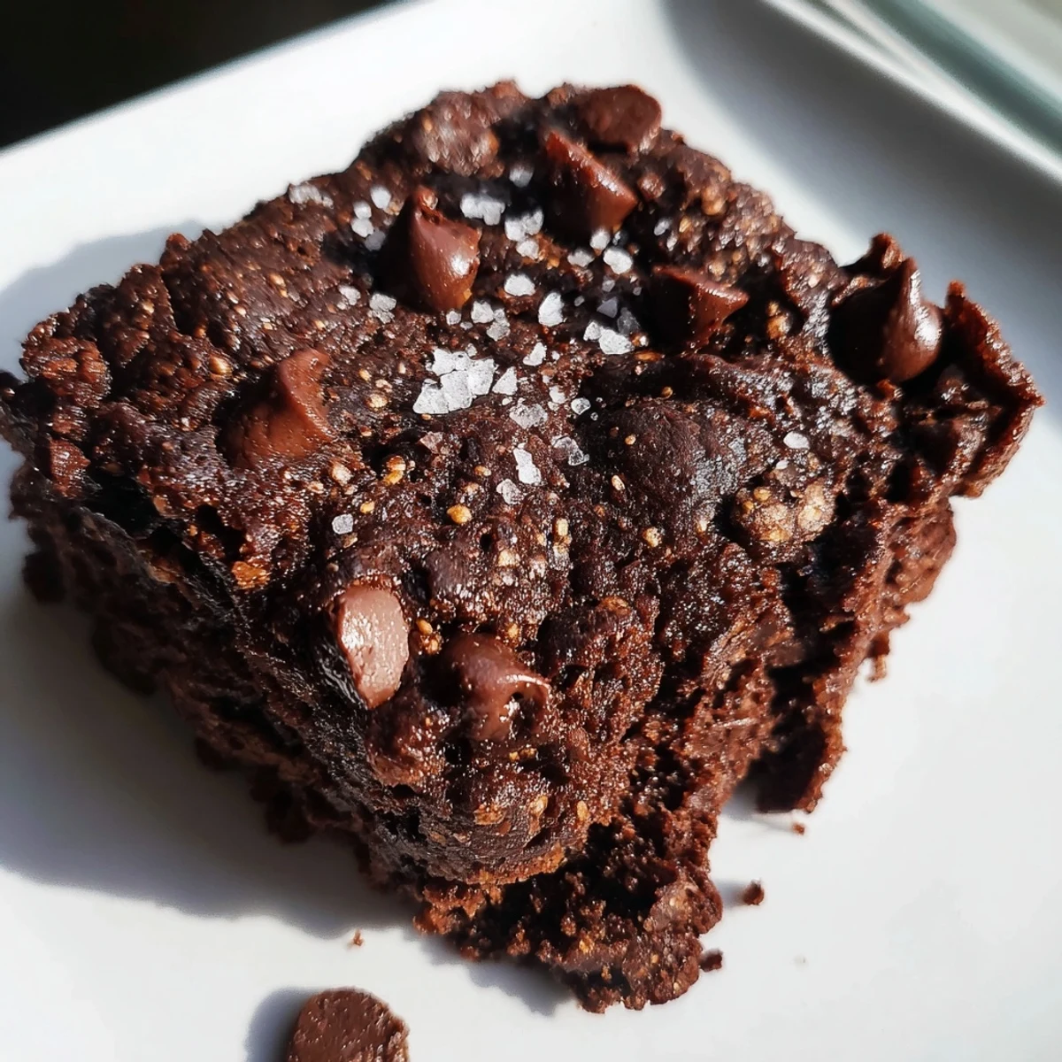 A slice of Gluten-Free Almond Flour Brownies with Sea Salt on a plate, ready to serve with a cold glass of milk.