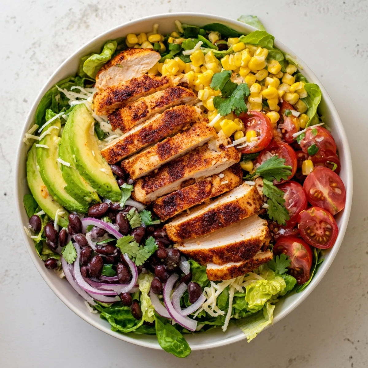 Close-up of Southwest Chicken Salad with Chipotle Lime Dressing, highlighting charred corn, creamy avocado, and fresh cilantro on a vibrant bed of greens.