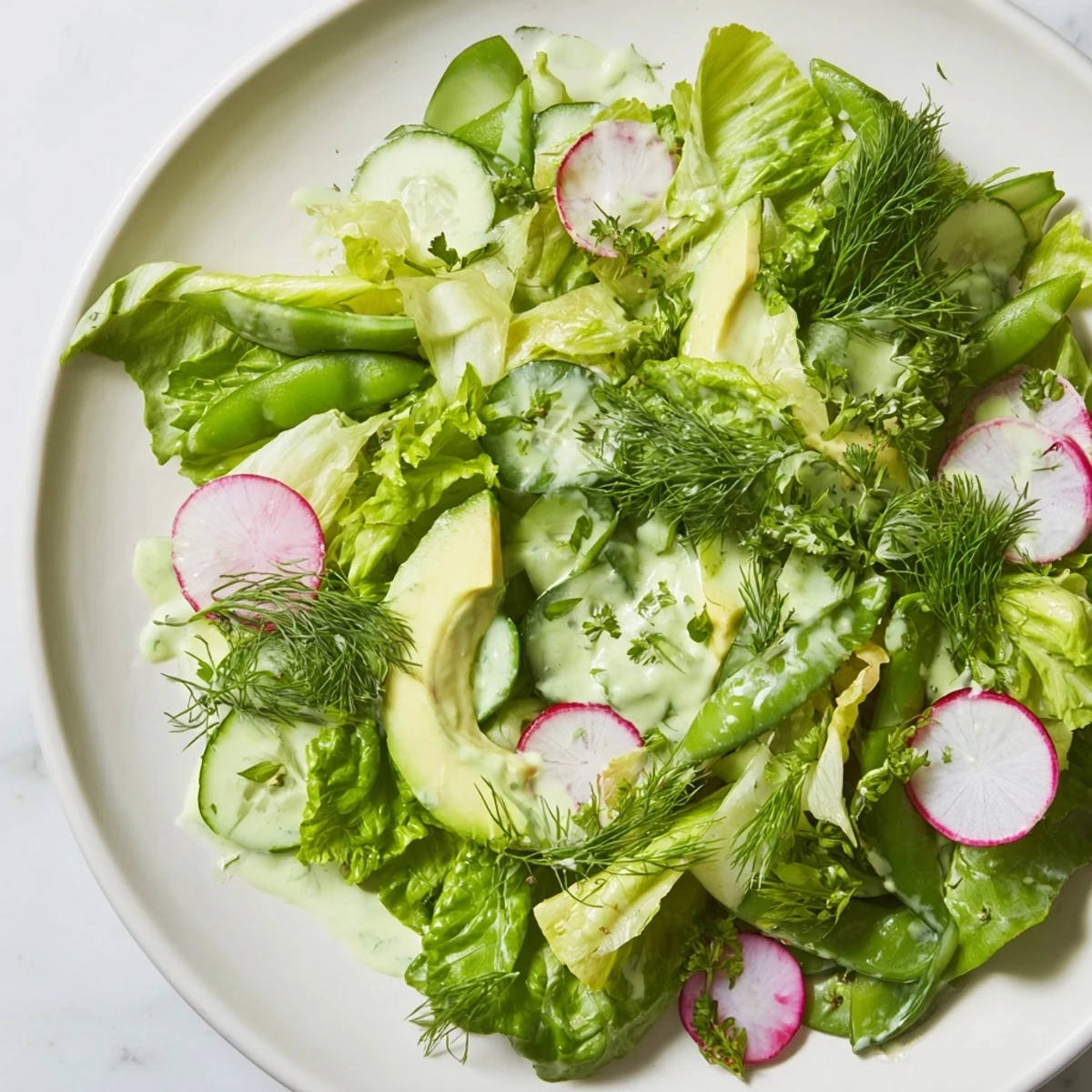 Freshly made Green Salad with Green Goddess Dressing, featuring crisp romaine, butter lettuce, and creamy avocado slices.