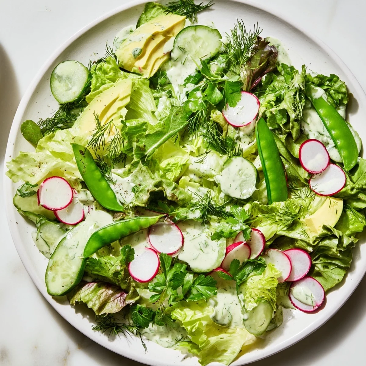 Green Salad with Green Goddess Dressing topped with bright radishes, cucumber slices, and crunchy sugar snap peas.
