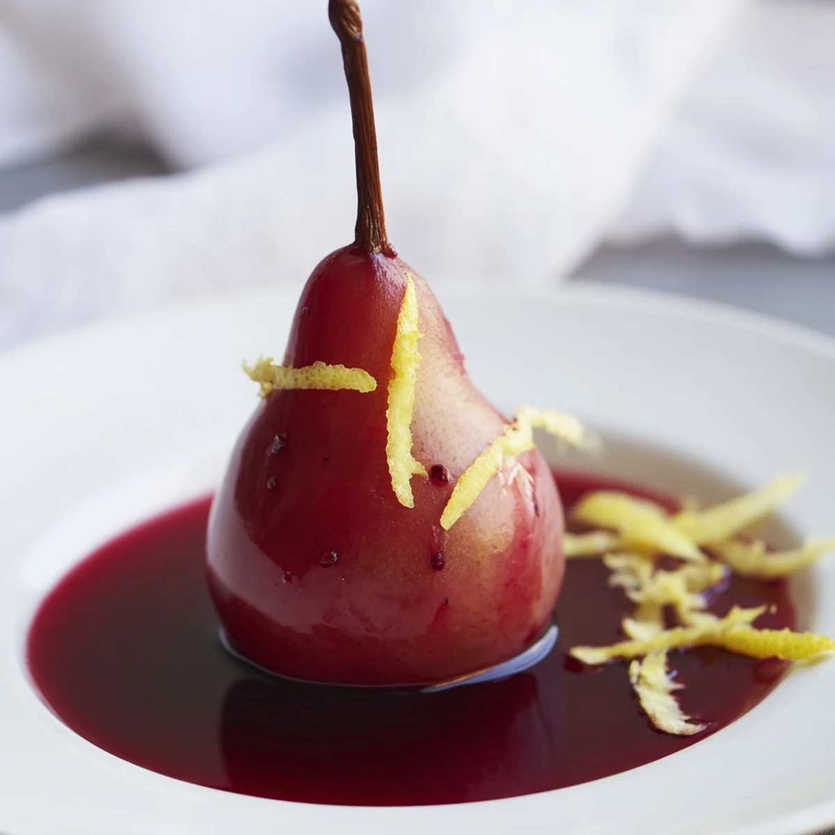 Romantic Poached Pears in Grape Juice are served warm with a dollop of whipped cream, perfect for a European-inspired dessert.