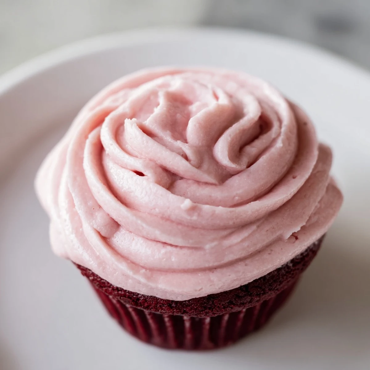 Moist Red Velvet Cupcakes with Pink Cream Cheese Frosting, topped with swirls of vibrant pink frosting and served on a white platter.