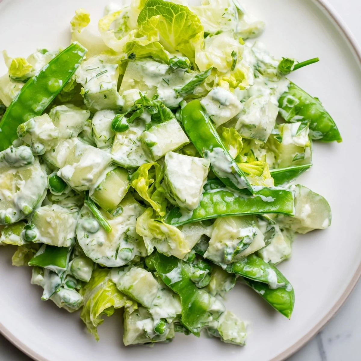 Green Goddess Salad with Cucumber and Avocado plated with romaine, snap peas, and herbs, ready for a light lunch.