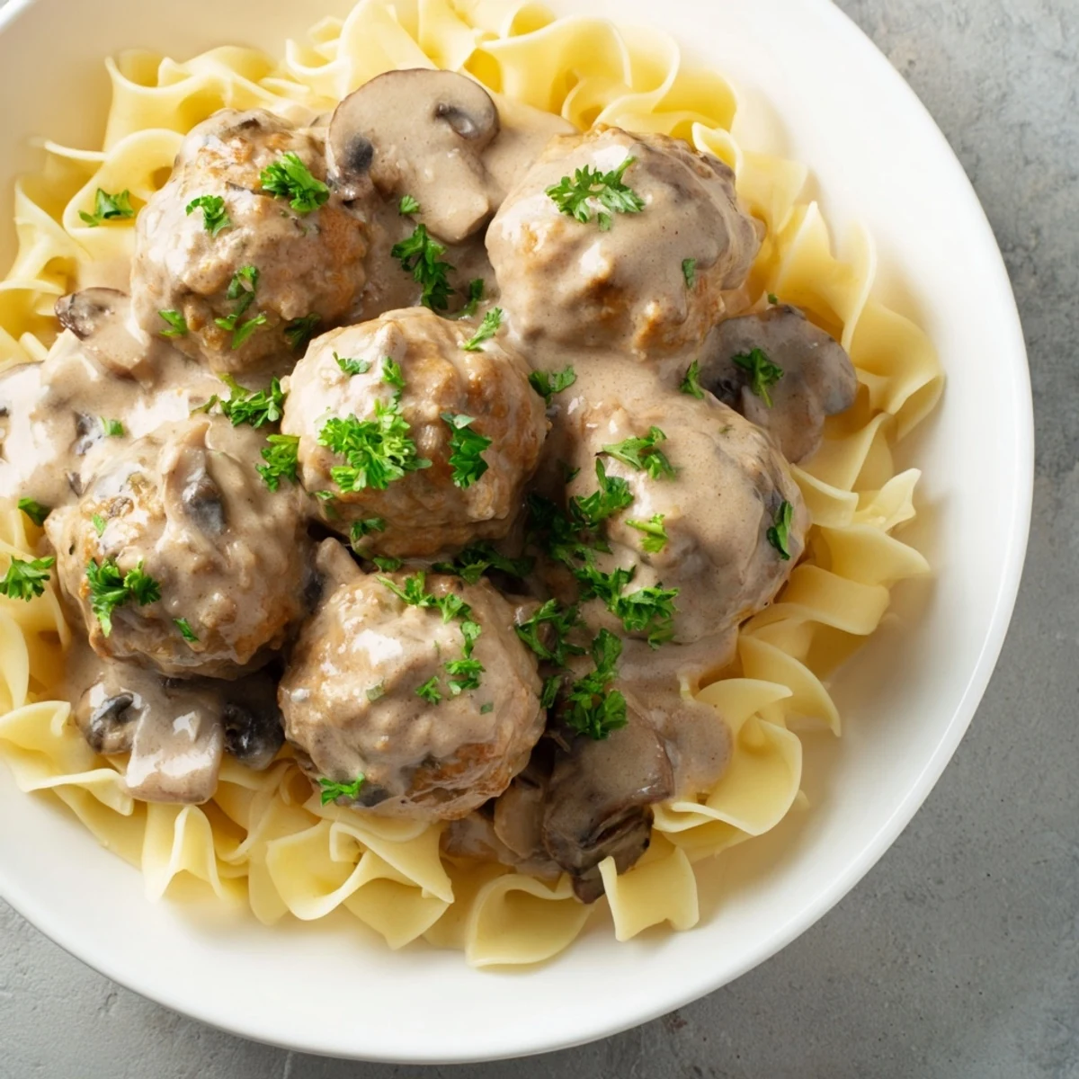 Savory turkey meatball stroganoff in a rich sauce, plated with egg noodles and a sprinkle of parsley.