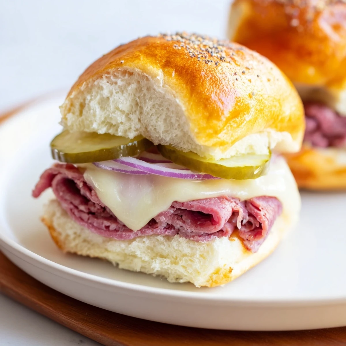 Golden Corned Beef Sliders with Swiss Cheese sit on a platter, melted cheese stretching between soft buns and pickles.