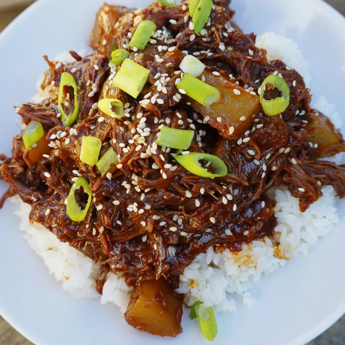 Delicious Crock Pot Korean Beef served in a bowl with rice, topped with fresh scallions and sesame seeds, highlighting the easy, crowd-pleasing meal.