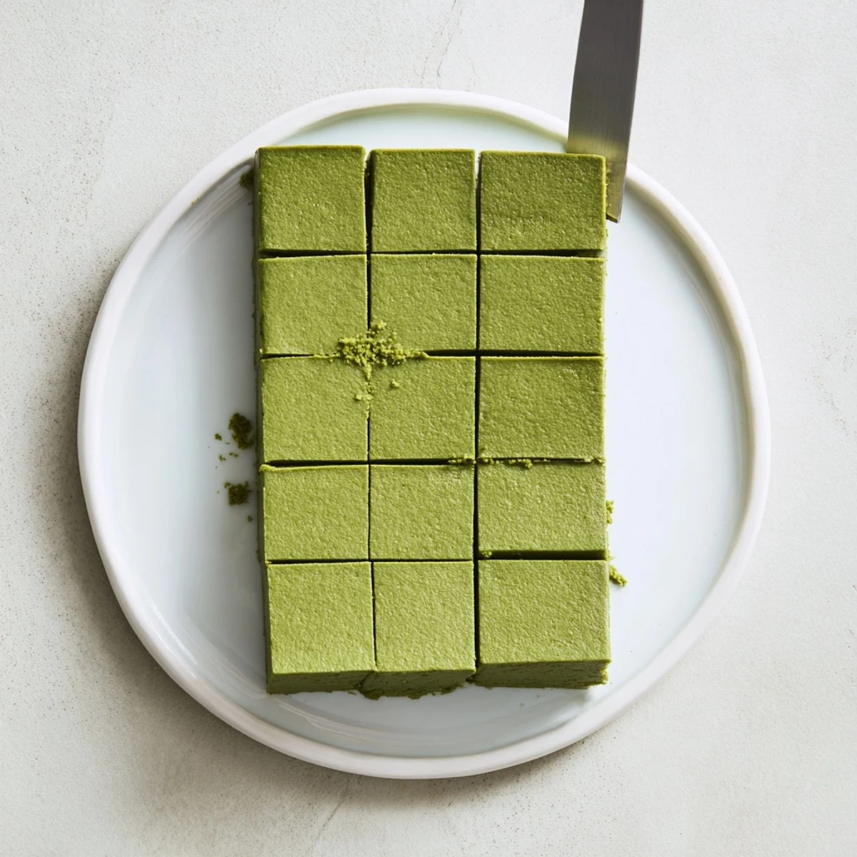 Decadent 5-Ingredient Matcha Halva confection with tahini and pistachios arranged on a white ceramic serving plate.