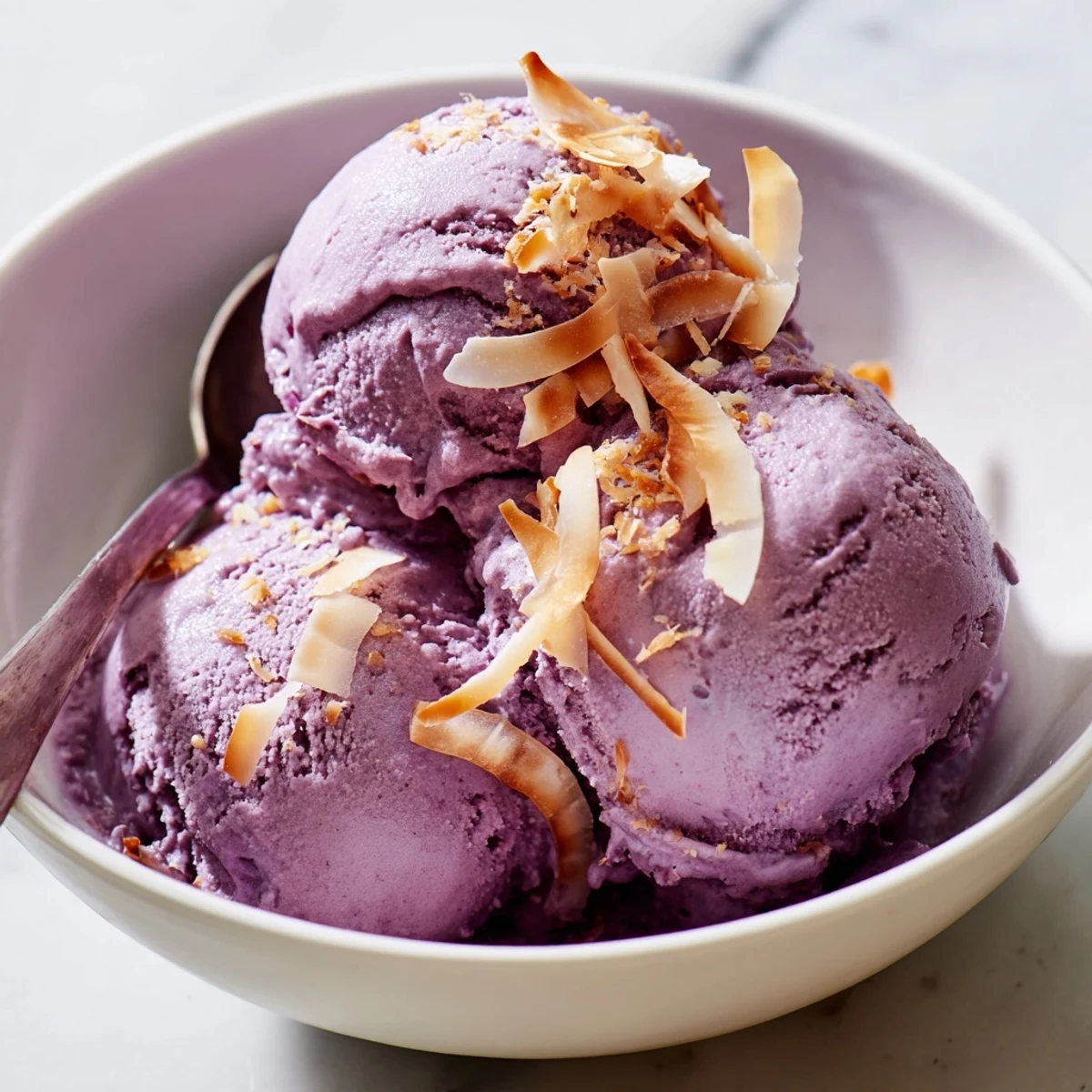 Ube ice cream is frozen in a rustic pan, showing smooth swirls and a vibrant violet hue.