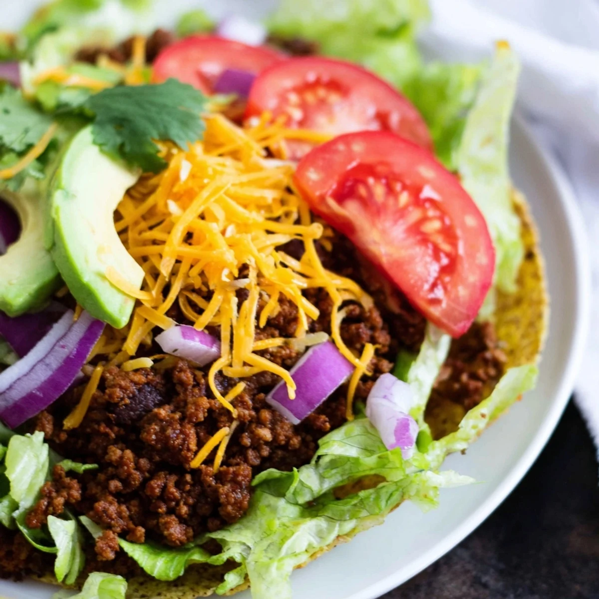 The Vegetarian Ground Beef Tacos are garnished with fresh cilantro and served with lime wedges on a rustic plate.