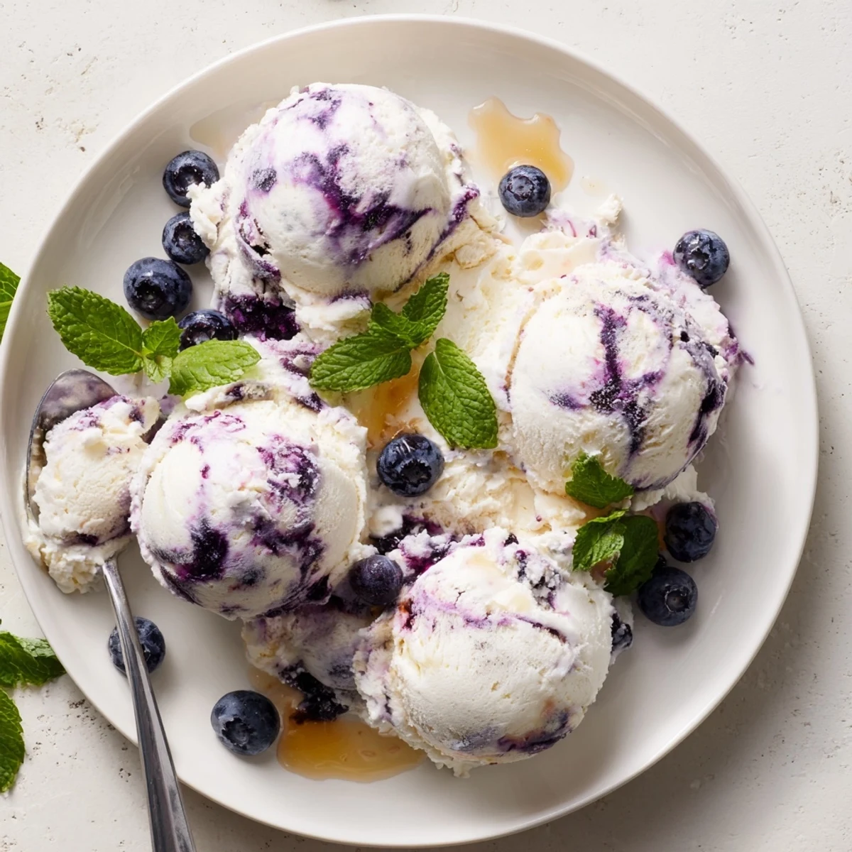 Blueberry Cottage Cheese Ice Cream served in a dish, topped with honey drizzle and mint garnish.
