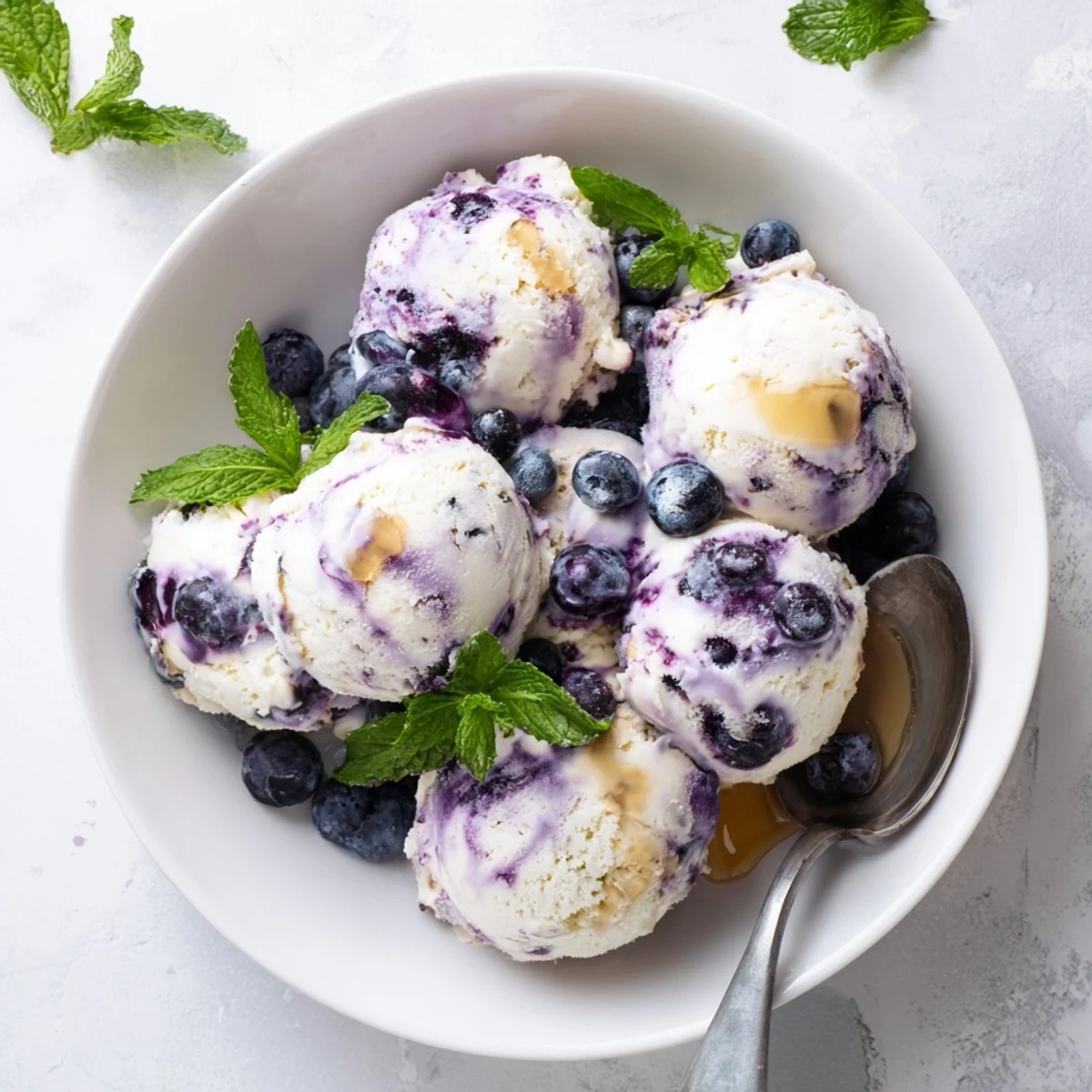 Scoop of frozen Blueberry Cottage Cheese Ice Cream next to a pint of fresh blueberries on a table.