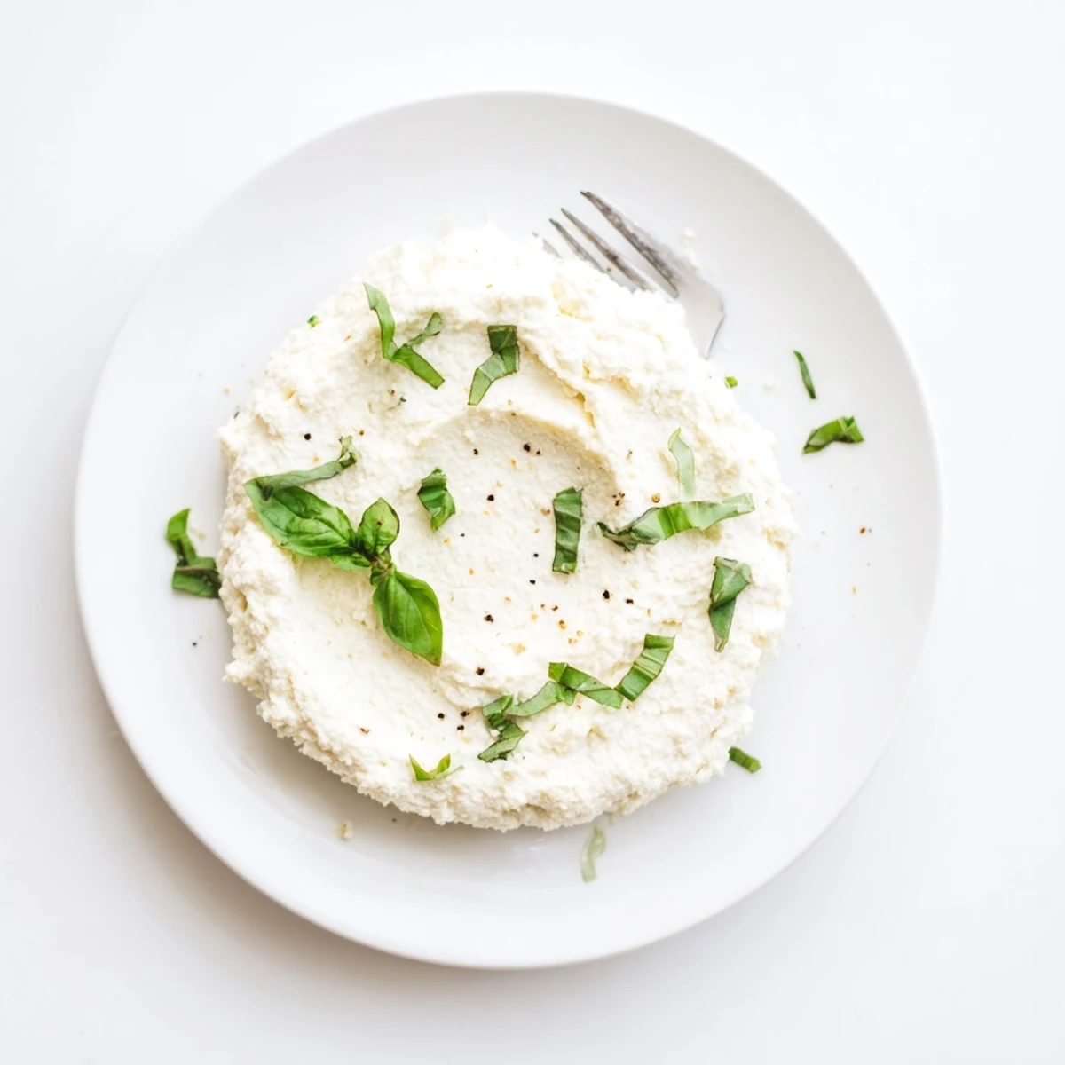 Crisp white tofu ricotta in a ceramic bowl garnished with fresh basil leaves, perfect for vegan lasagna.  