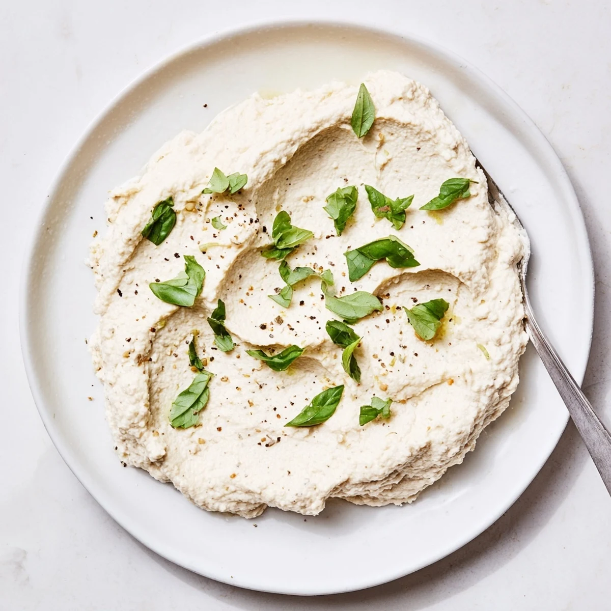 Smooth tofu ricotta being scooped into a stuffed shell, showcasing a texture like traditional ricotta.