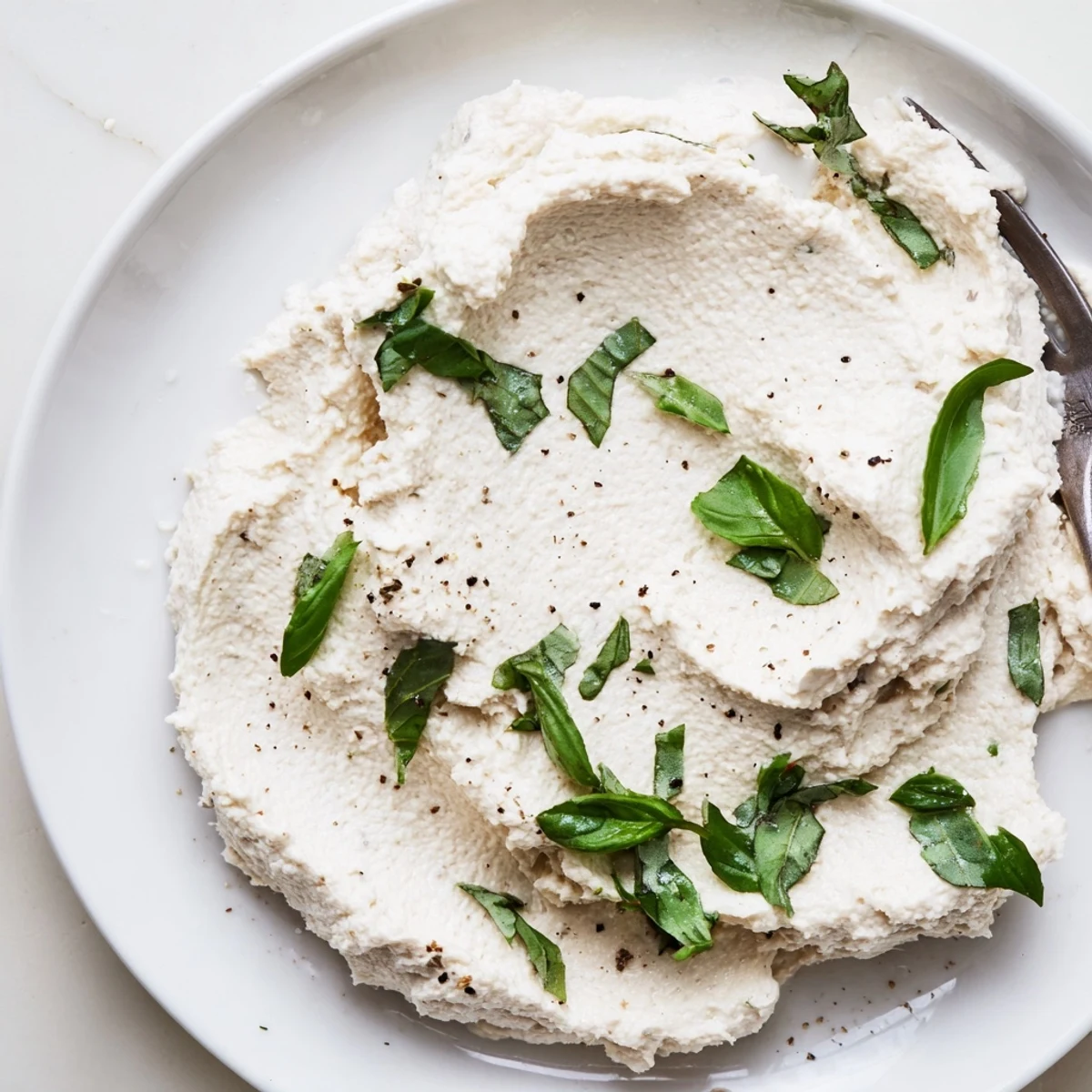 Creamy tofu ricotta spread over toasted crostini with diced tomatoes, a vibrant dairy-free appetizer idea.  