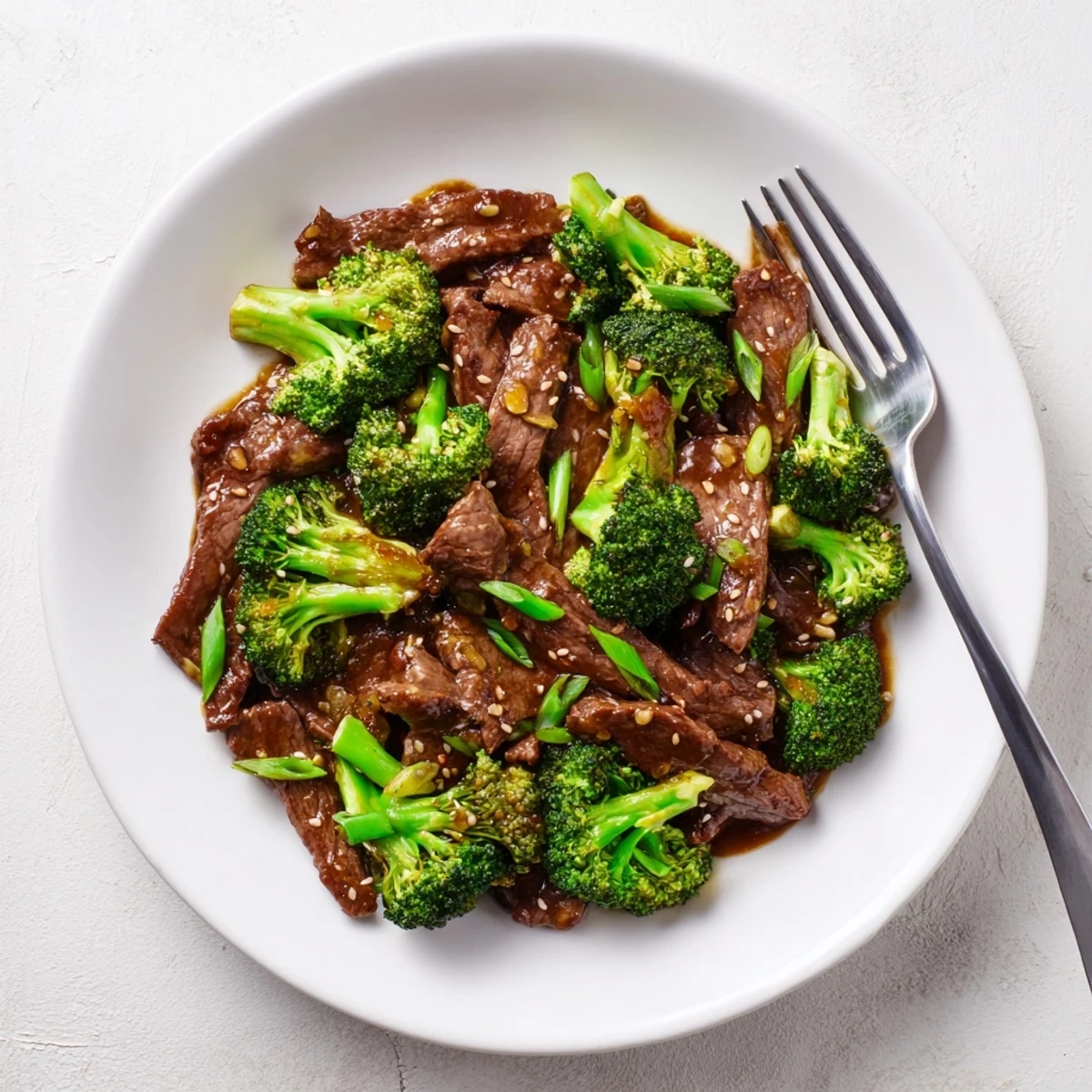 Close-up of Better Than Takeout Beef With Broccoli sizzling in a wok, featuring caramelized beef strips, bright green broccoli, and aromatic garlic and ginger.