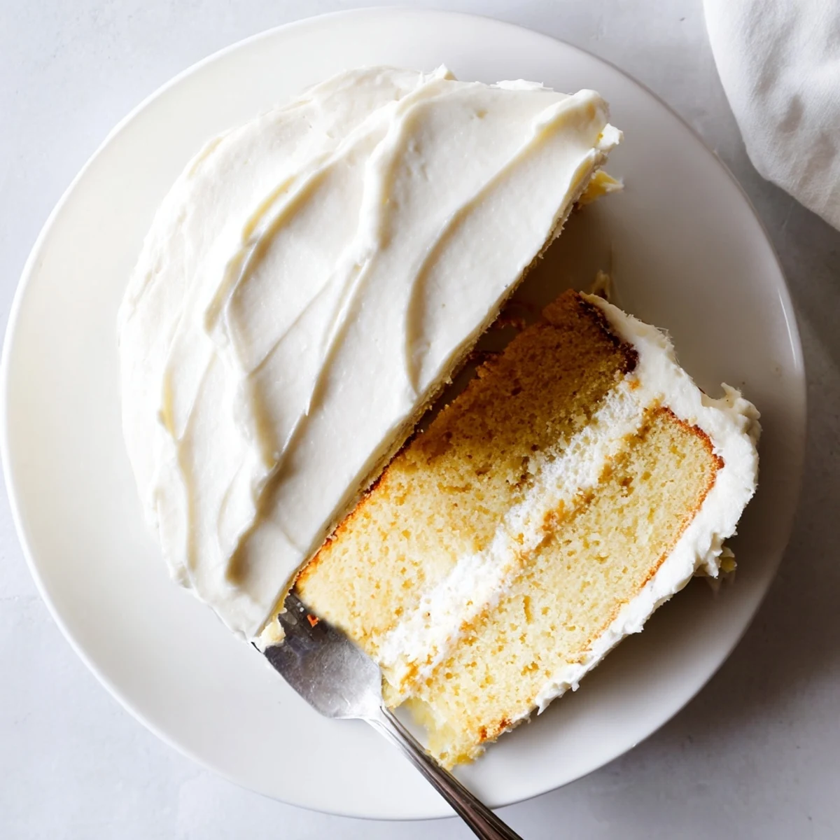 Close-up of a slice of Perfect Vanilla Cake revealing moist crumb and fluffy buttercream frosting texture.