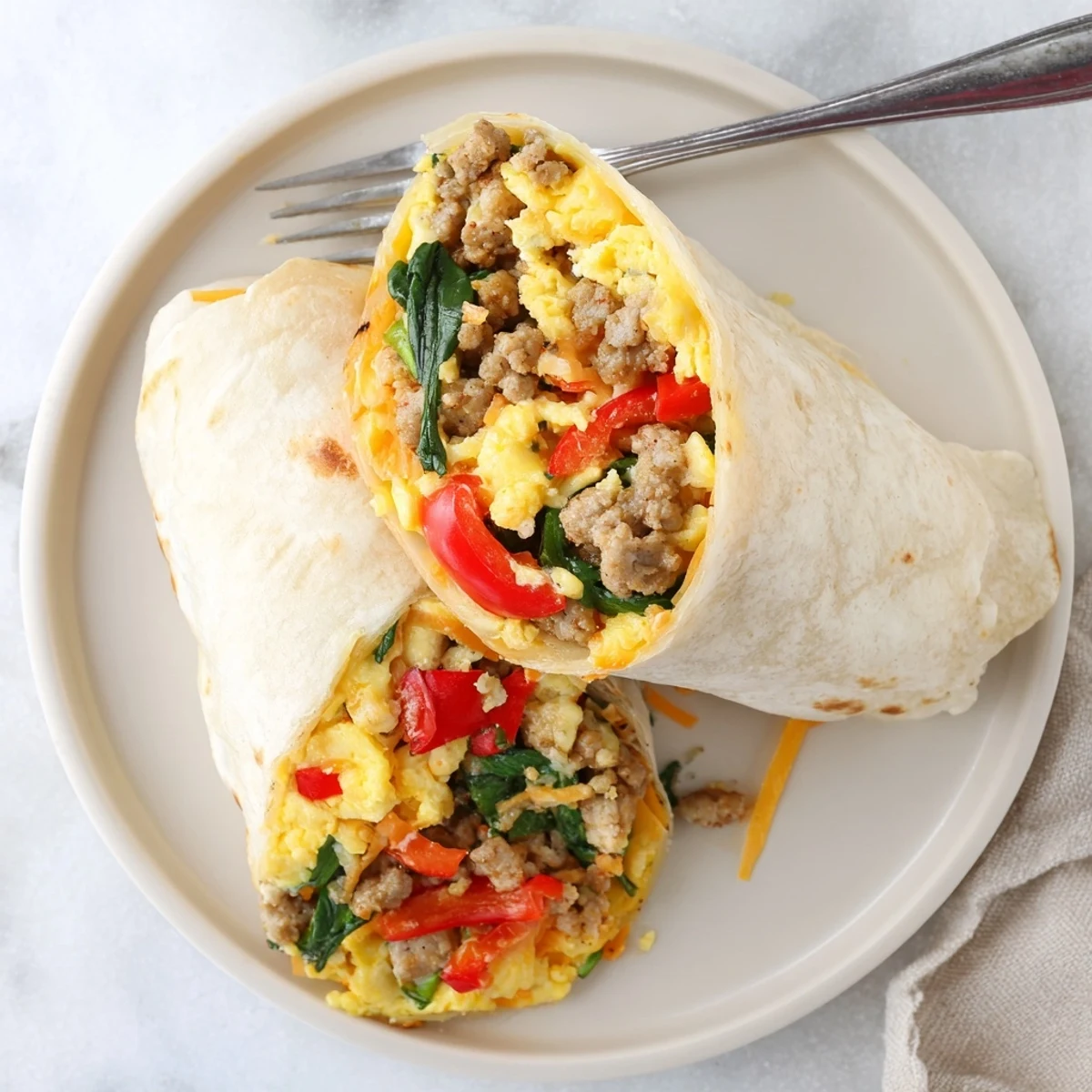 Golden make-ahead breakfast burritos filled with scrambled eggs, sausage, cheese, and colorful vegetables