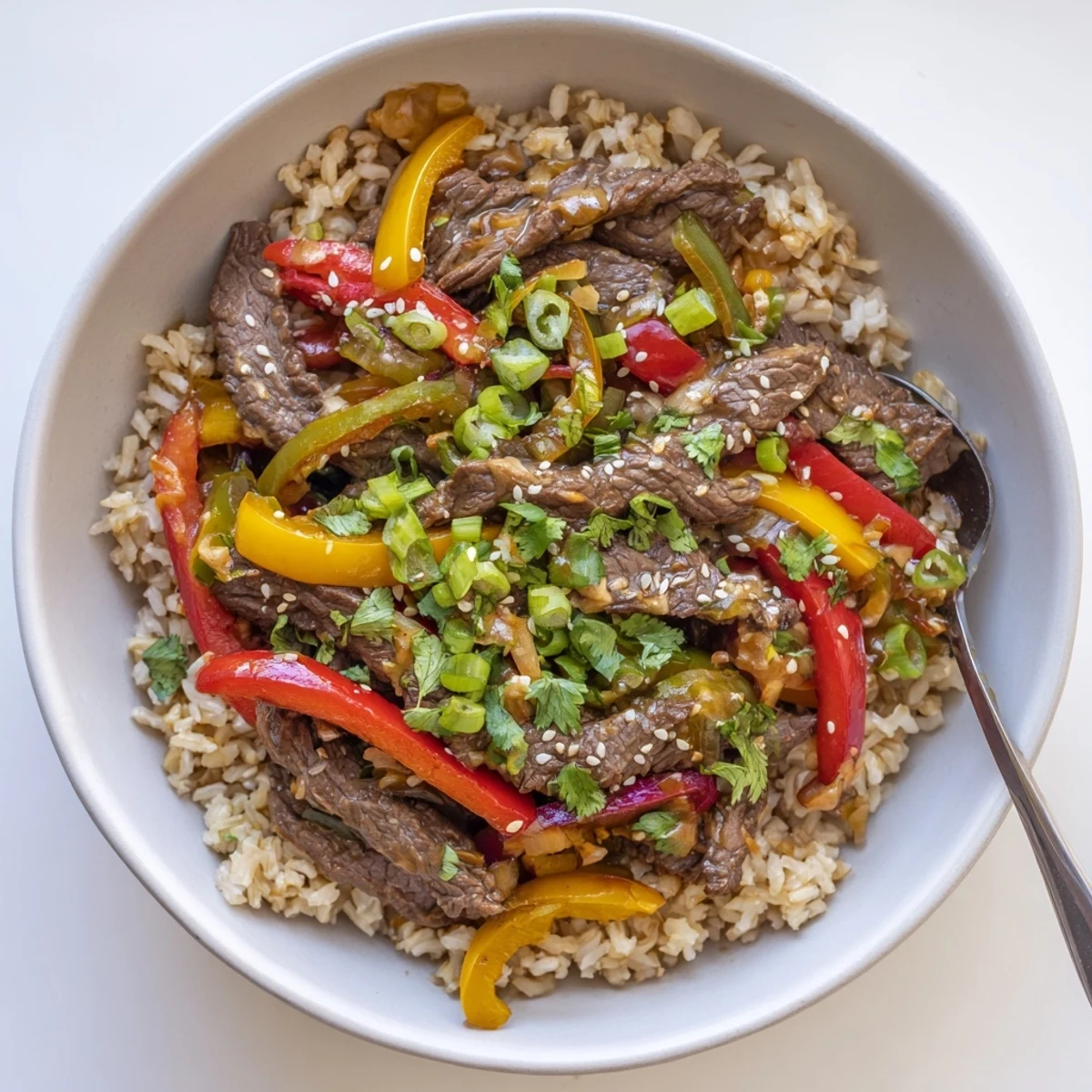 Healthy beef and pepper rice bowl featuring tender beef strips and colorful bell peppers in garlic-ginger sauce over fluffy brown rice