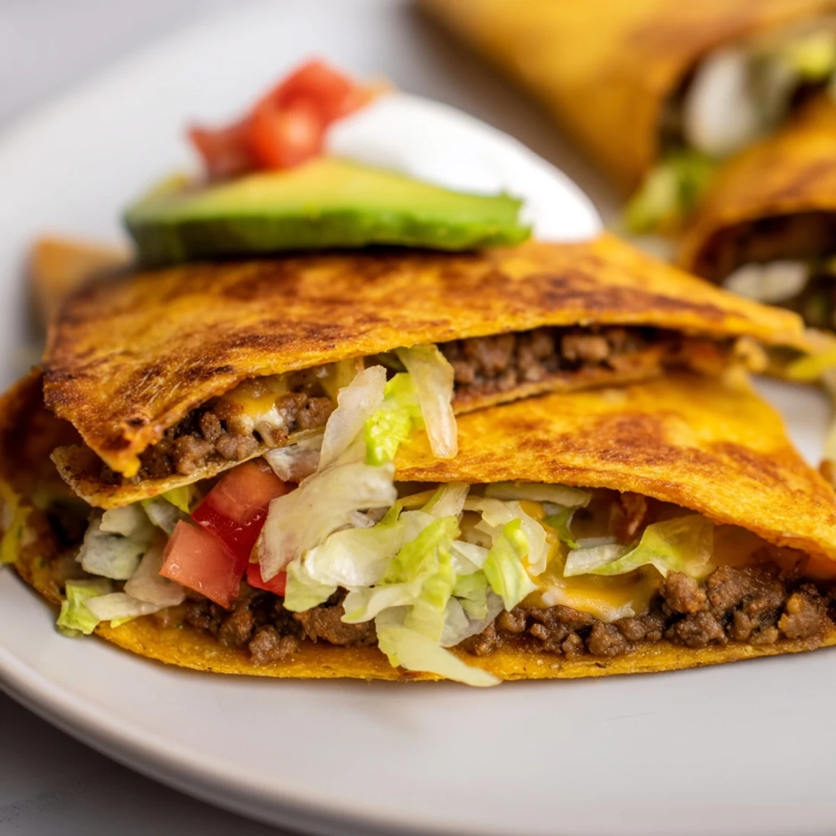 Sliced keto crunchwrap revealing layers of taco-seasoned ground beef, fresh avocado, jalapeños, and cheese inside a toasted almond flour tortilla
