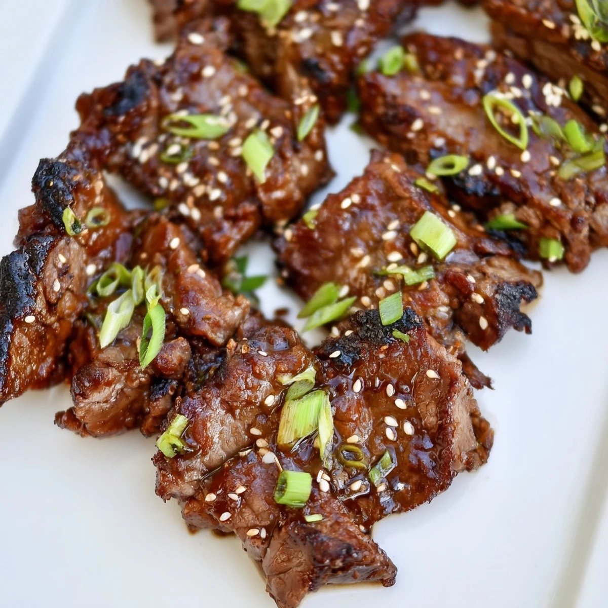 Plate of Korean Galbi ribs garnished with green onions and toasted sesame seeds after grilling