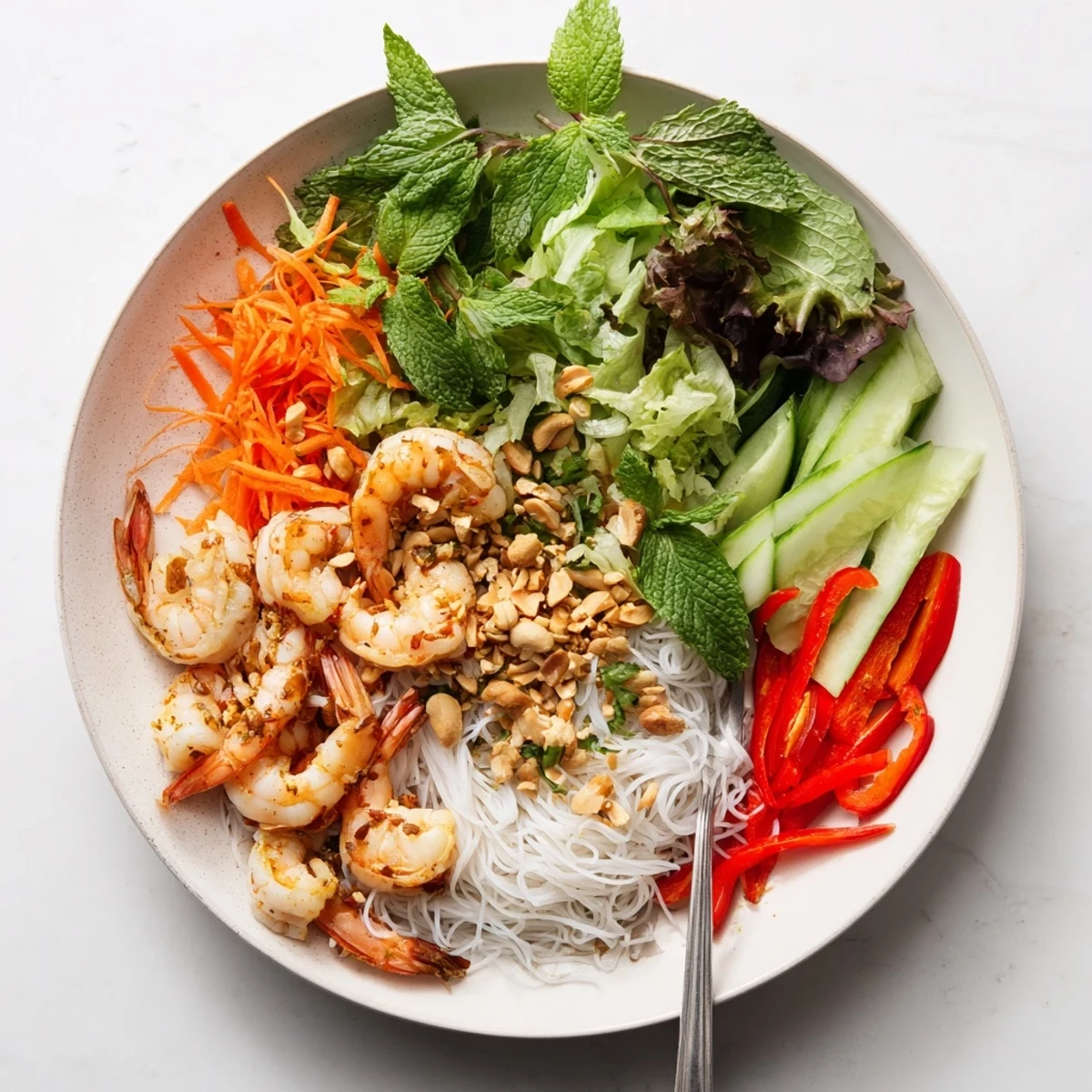 Fresh spring roll salad featuring tender shrimp, julienned vegetables, rice noodles, and spicy ginger dressing topped with crushed peanuts