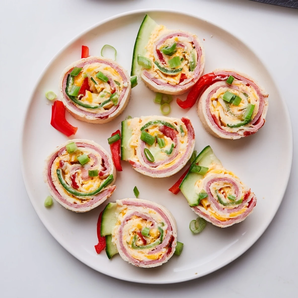Plate of keto ham roll ups filled with creamy cheese and colorful julienned vegetables