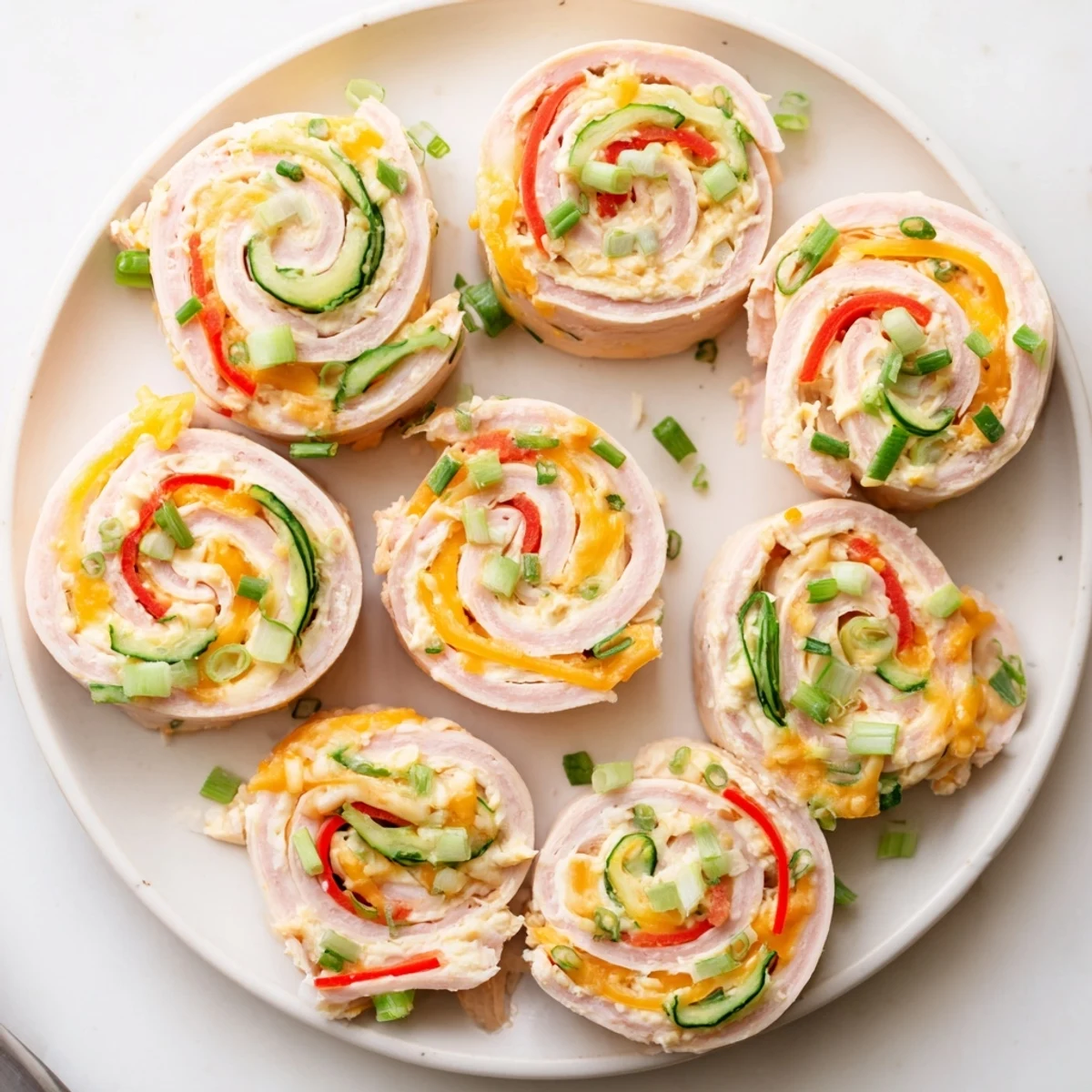 Sliced keto ham roll ups showcasing cream cheese filling and crisp red bell pepper strips