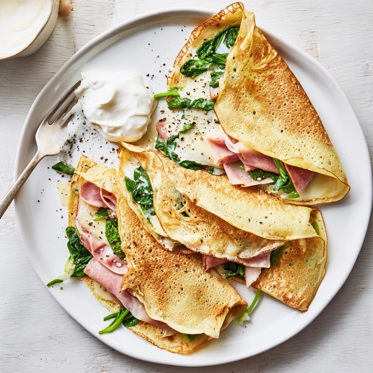 Delicate thin savory crepes folded into quarters with bubbling cheese and fresh green spinach filling