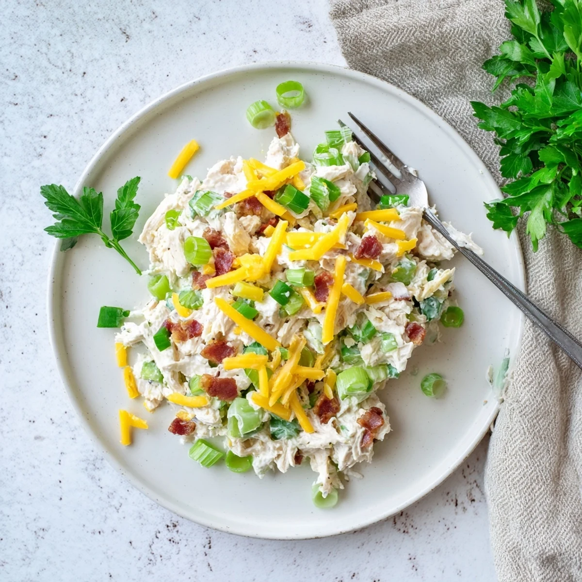 Close up of low carb jalapeno popper cottage cheese chicken salad featuring chunks of tender chicken and melted cheddar cheese in a rustic ceramic bowl