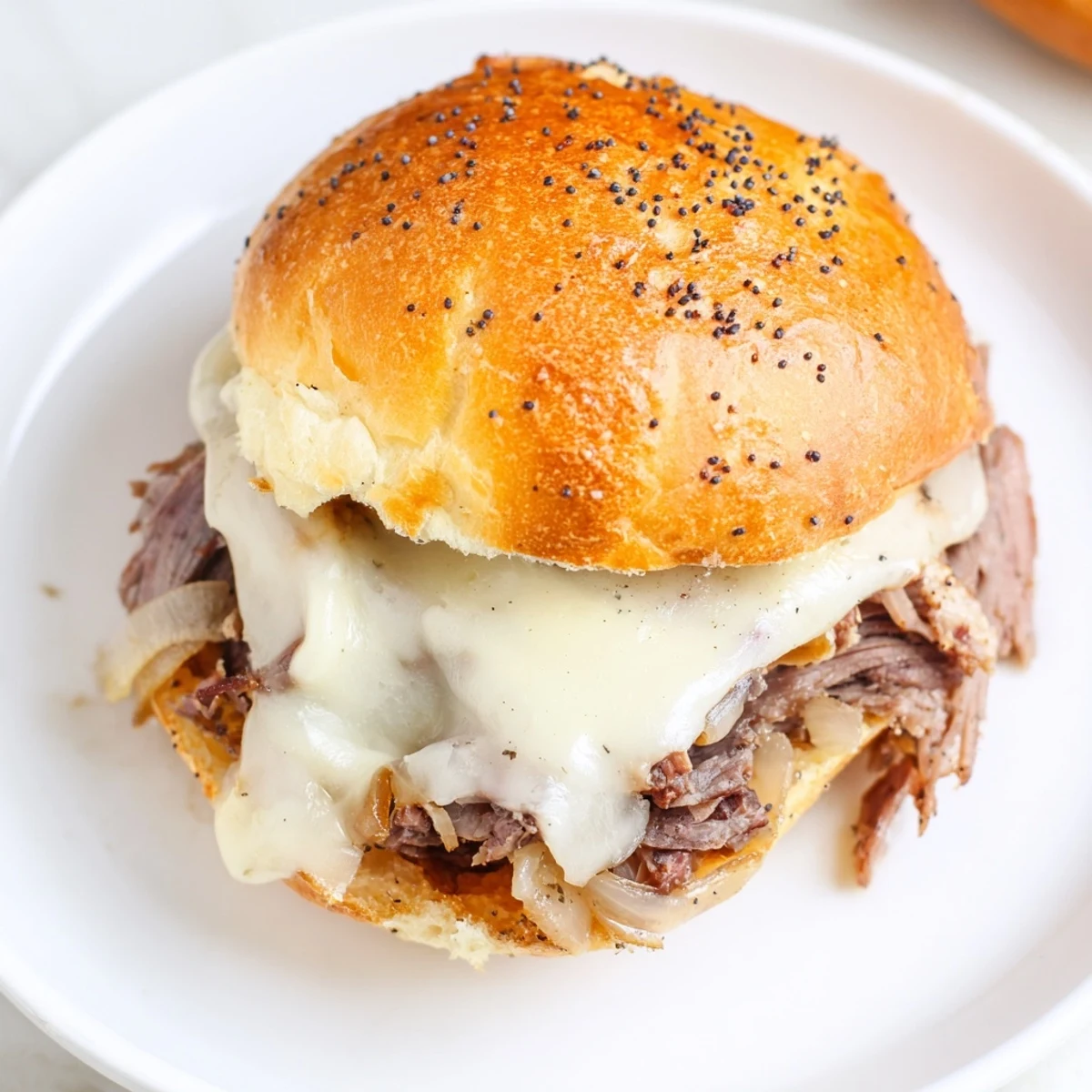 Baked French dip sliders topped with poppy seeds and gooey cheese ready for party entertaining