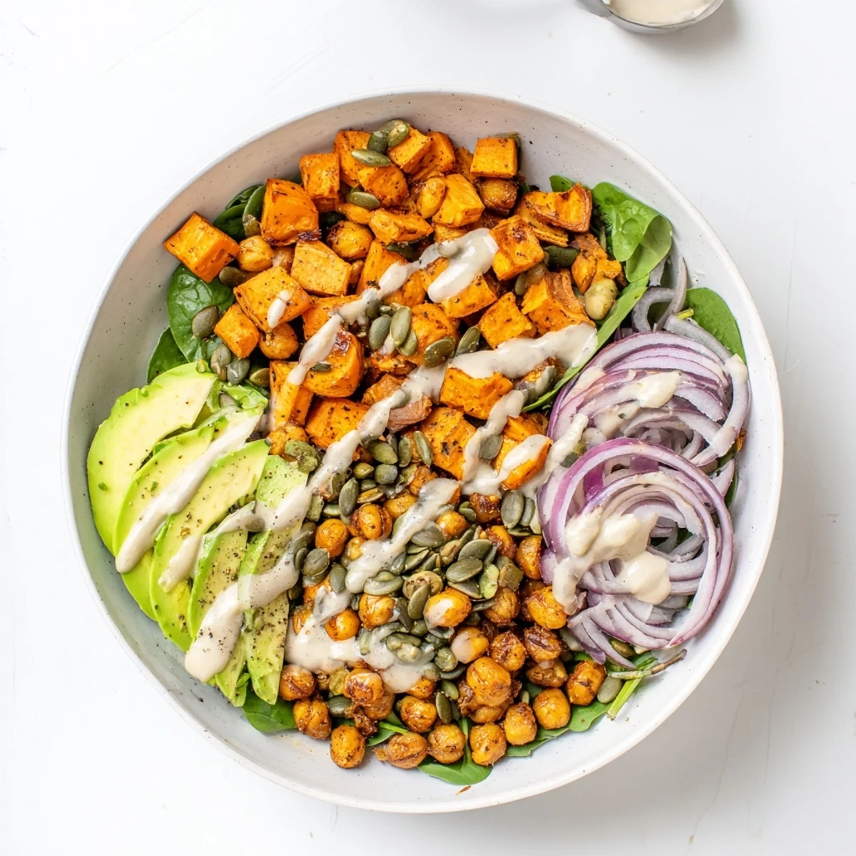 Golden roasted sweet potatoes and crispy chickpeas served over fresh greens with creamy tahini dressing drizzled on top
