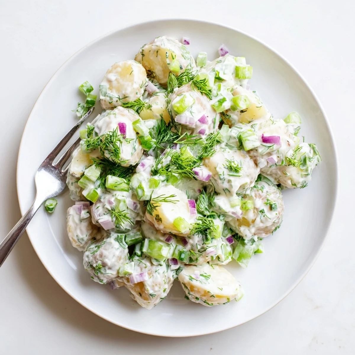 Lightened-up potato salad tossed in tangy Greek yogurt dressing with crunchy vegetables and chopped dill.