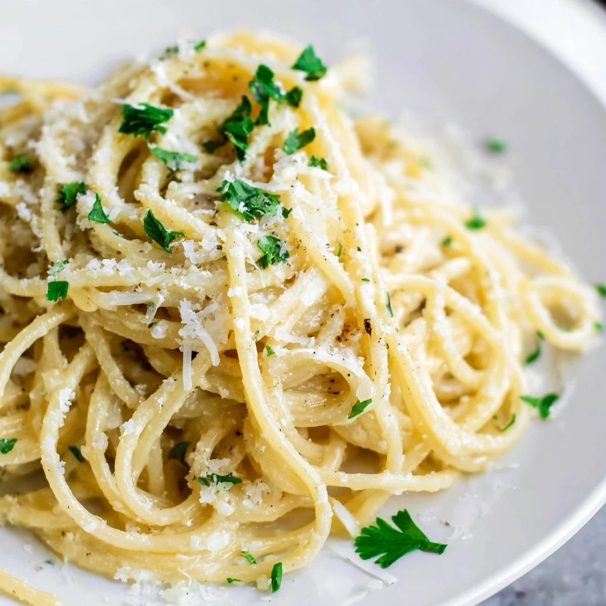 Steam rises from a heaping plate of Cheesy Garlic Parmesan Spaghetti topped with extra grated Parmesan cheese