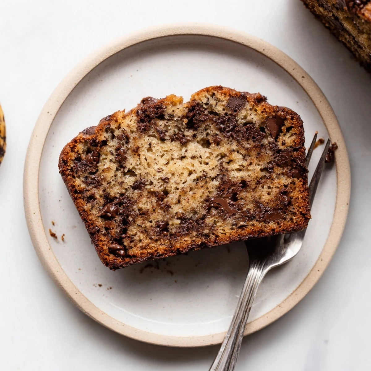 Golden chocolate chip banana bread loaf with melted chocolate chunks on a rustic wooden board