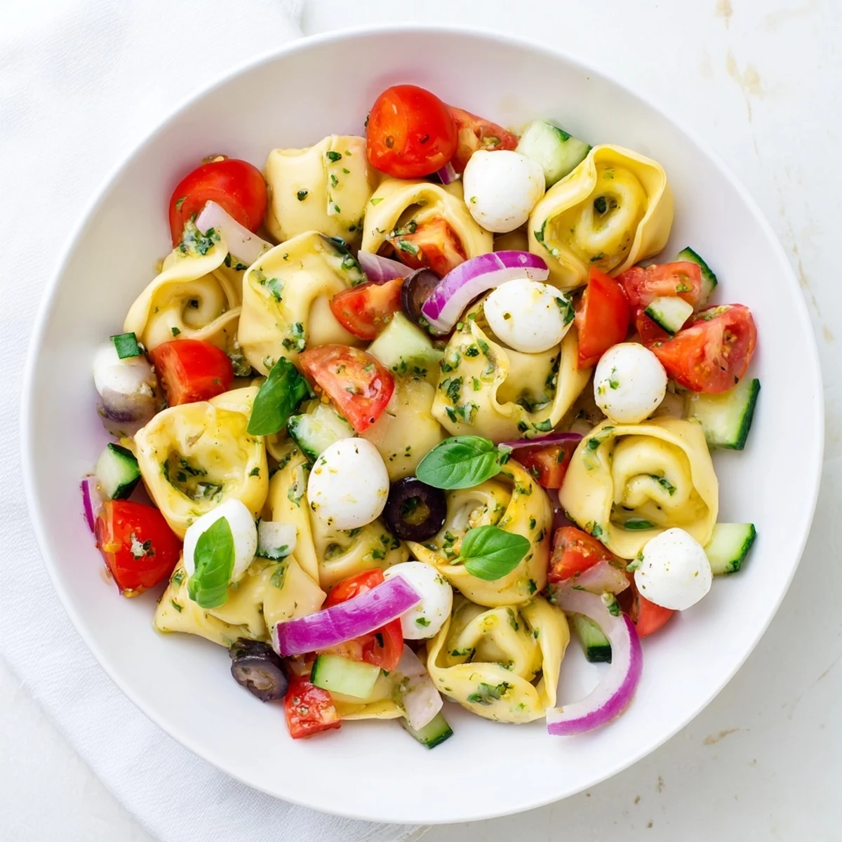 Colorful tortellini pasta salad with cherry tomatoes, olives, and zesty Italian dressing in a serving bowl