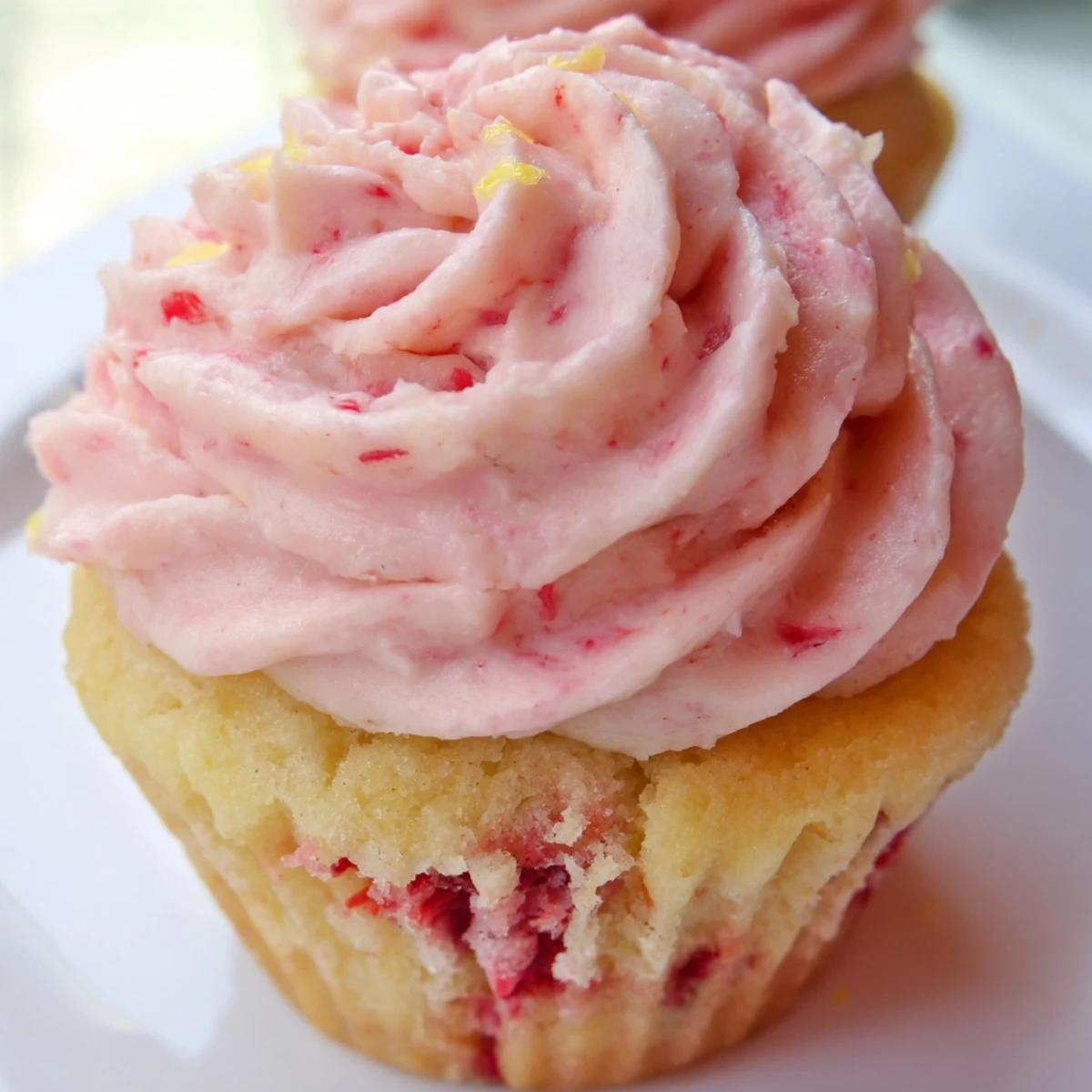 Tall fluffy strawberry lemonade cupcakes with swirled pink frosting and fresh berry garnish