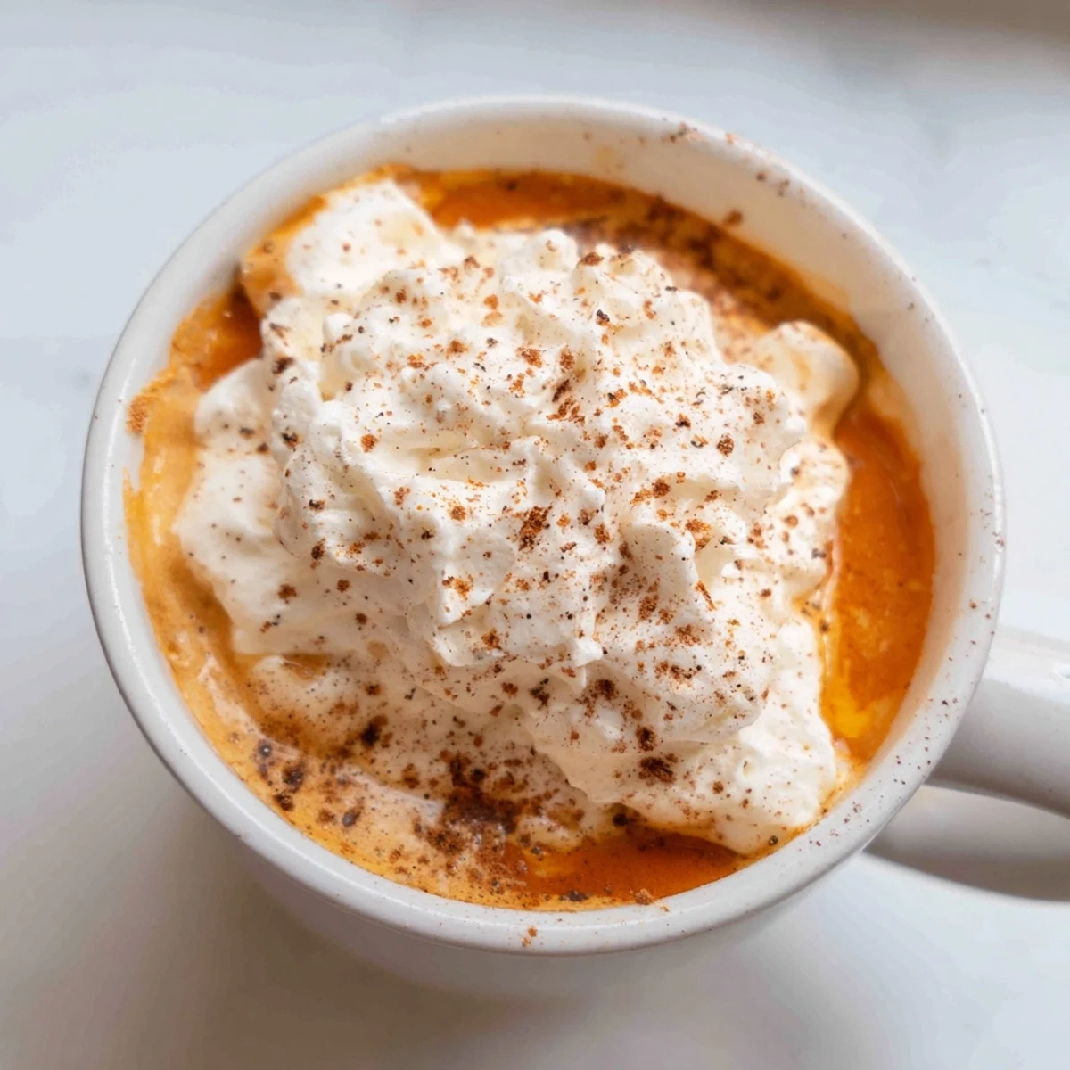 Creamy homemade pumpkin spice latte topped with whipped cream and cinnamon dust