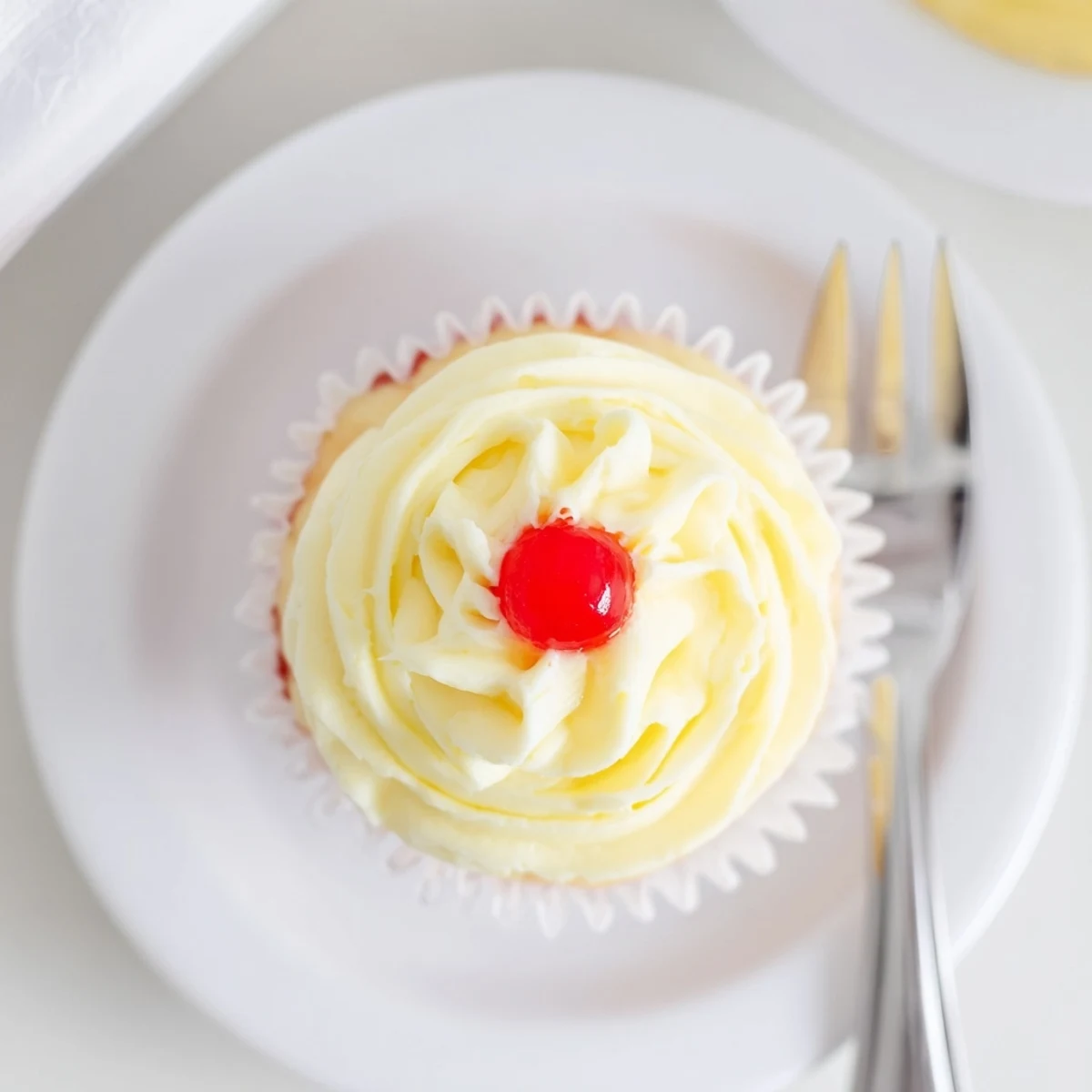 Golden Dole Whip Cupcakes topped with creamy pineapple whipped frosting and cherry garnish