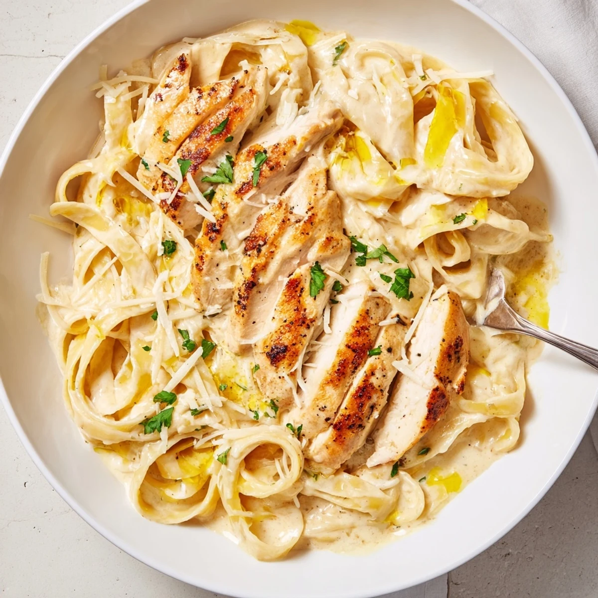 Creamy Garlic Chicken Pasta steaming on plate with parsley and grated Parmesan