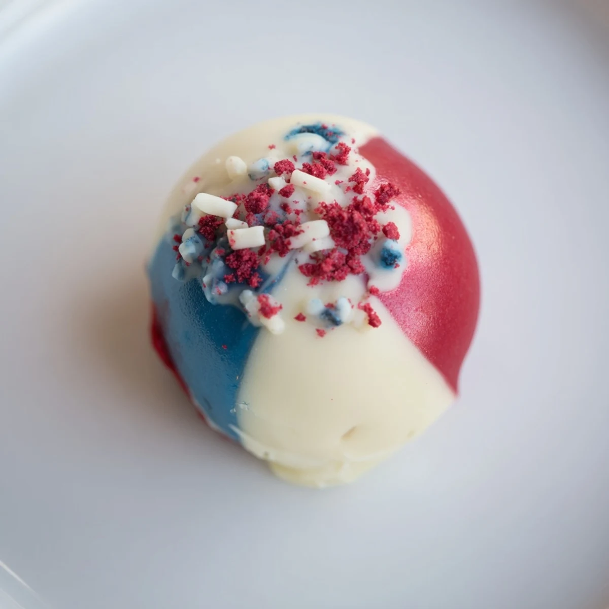 Stacked Fourth of July Truffles on parchment, creamy vanilla center and berry bursts