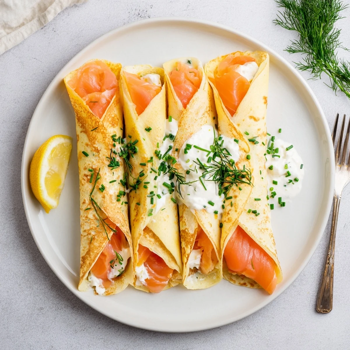 Golden smoked salmon crepes rolled with creamy herbed cheese filling and fresh dill garnish
