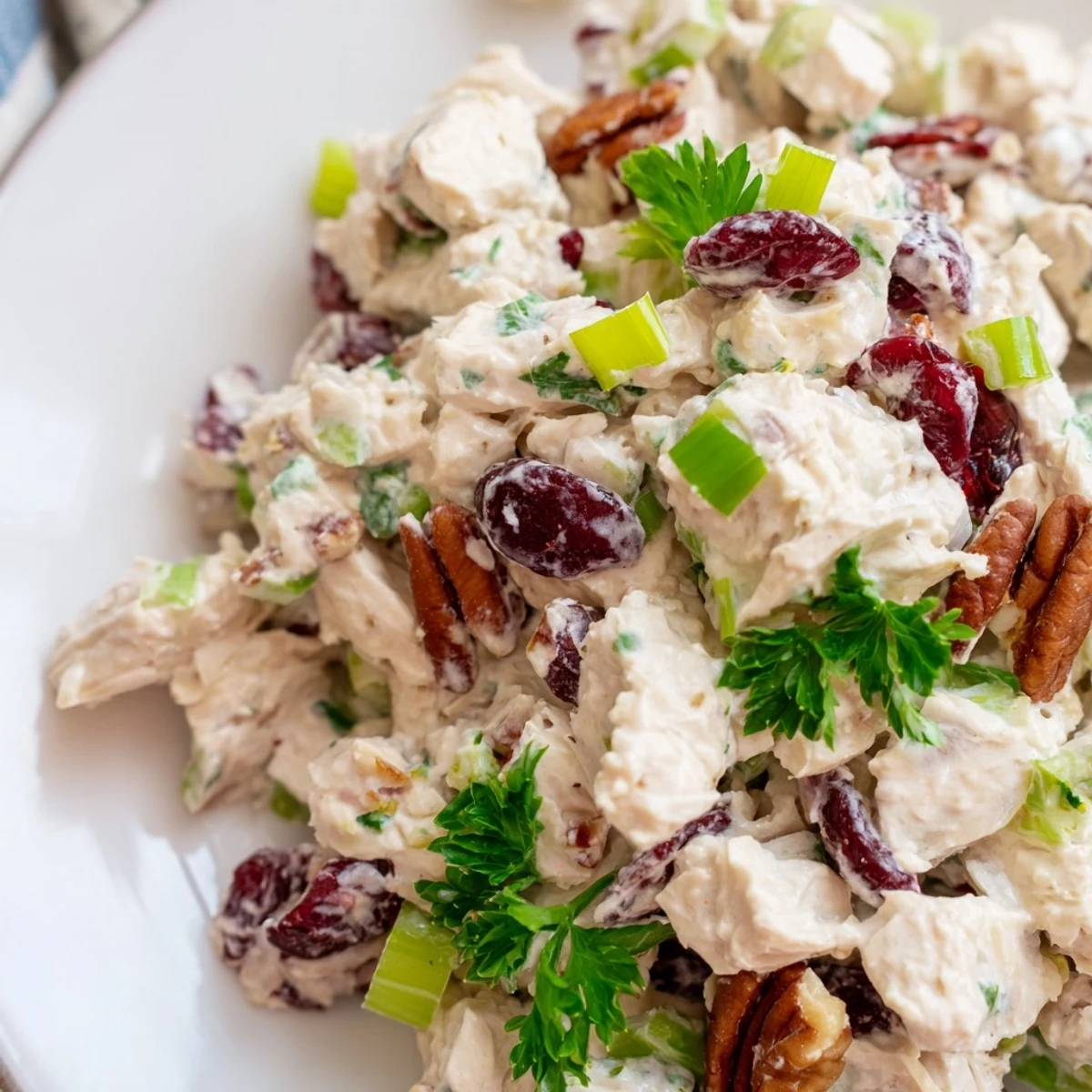 Creamy cranberry pecan chicken salad served in a white bowl with fresh parsley garnish