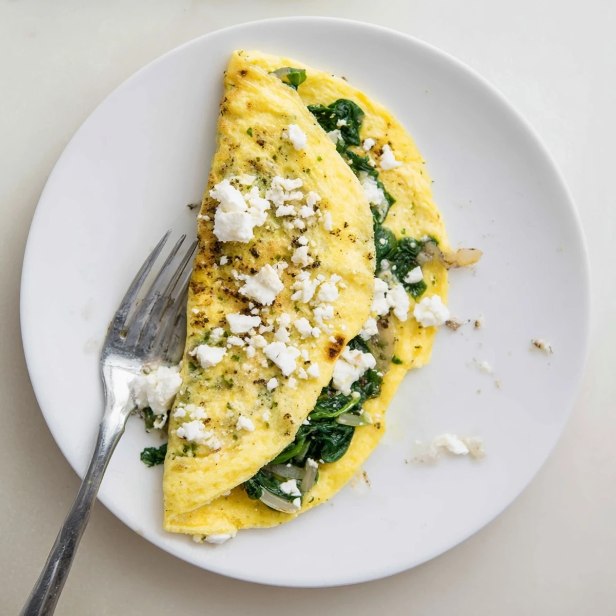 Savory Mediterranean spinach feta omelet recipe with wilted green spinach inside