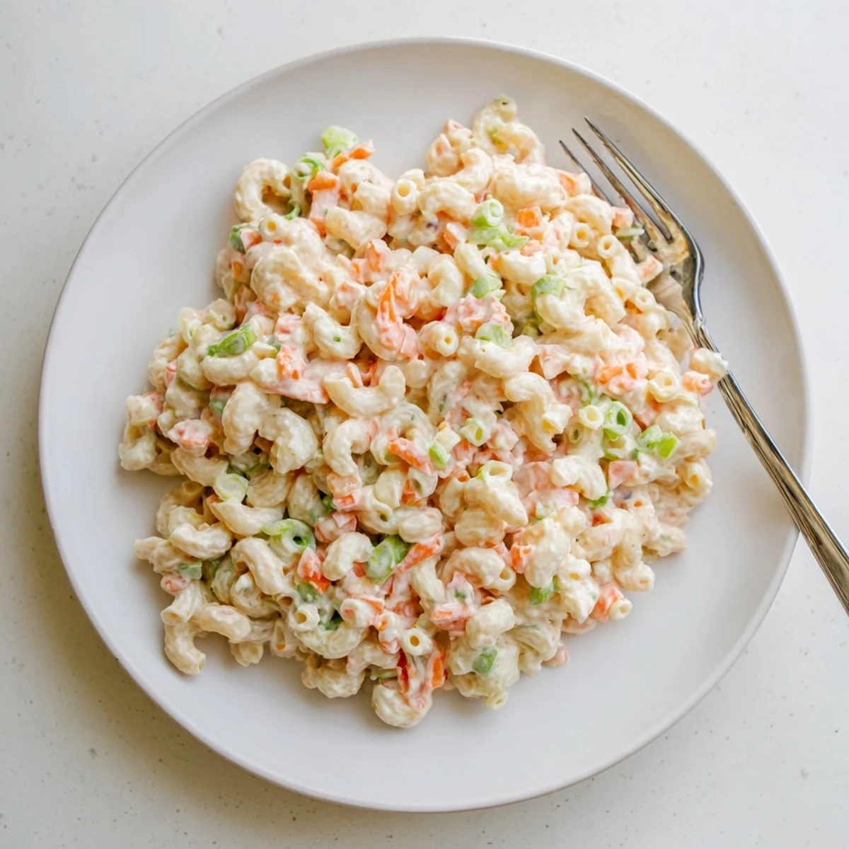 Golden macaroni salad mounded high with fresh green onions and carrot bits for an authentic Hawaiian plate lunch staple