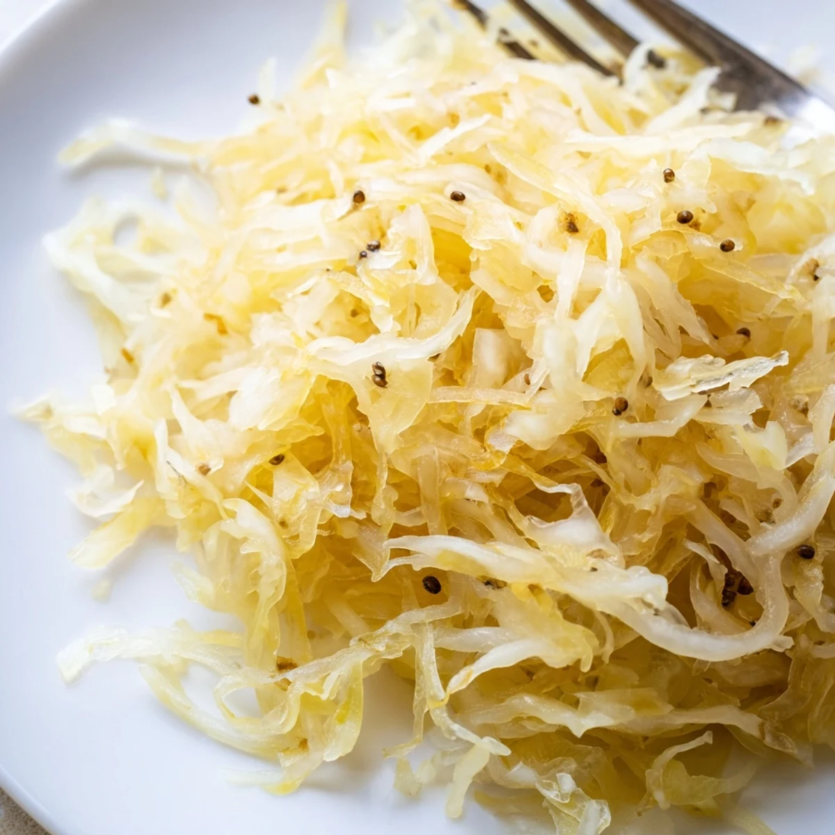 Golden fermented sauerkraut piled high in a glass jar, showcasing tangy shredded cabbage texture