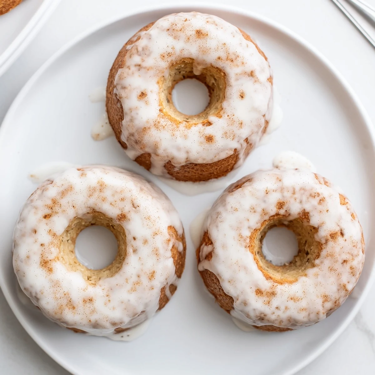 Golden baked banana bread donuts drizzled with sweet cinnamon glaze on a wire cooling rack