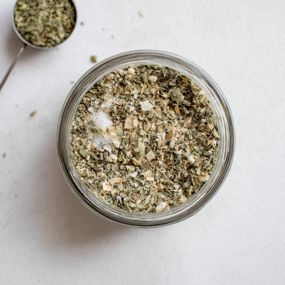 Glass jar filled with aromatic homemade Dehydrated Tzatziki Seasoning Mix, featuring vibrant green dill and dried cucumber flakes
