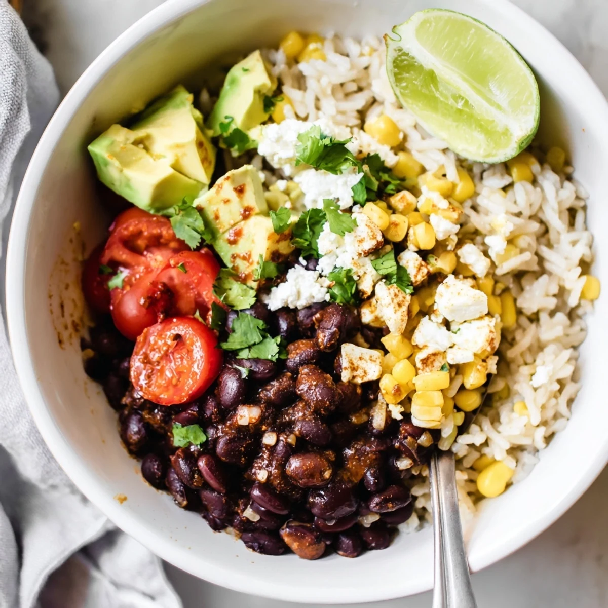 Hearty black bean and rice bowl topped with fresh avocado and bright lime wedges