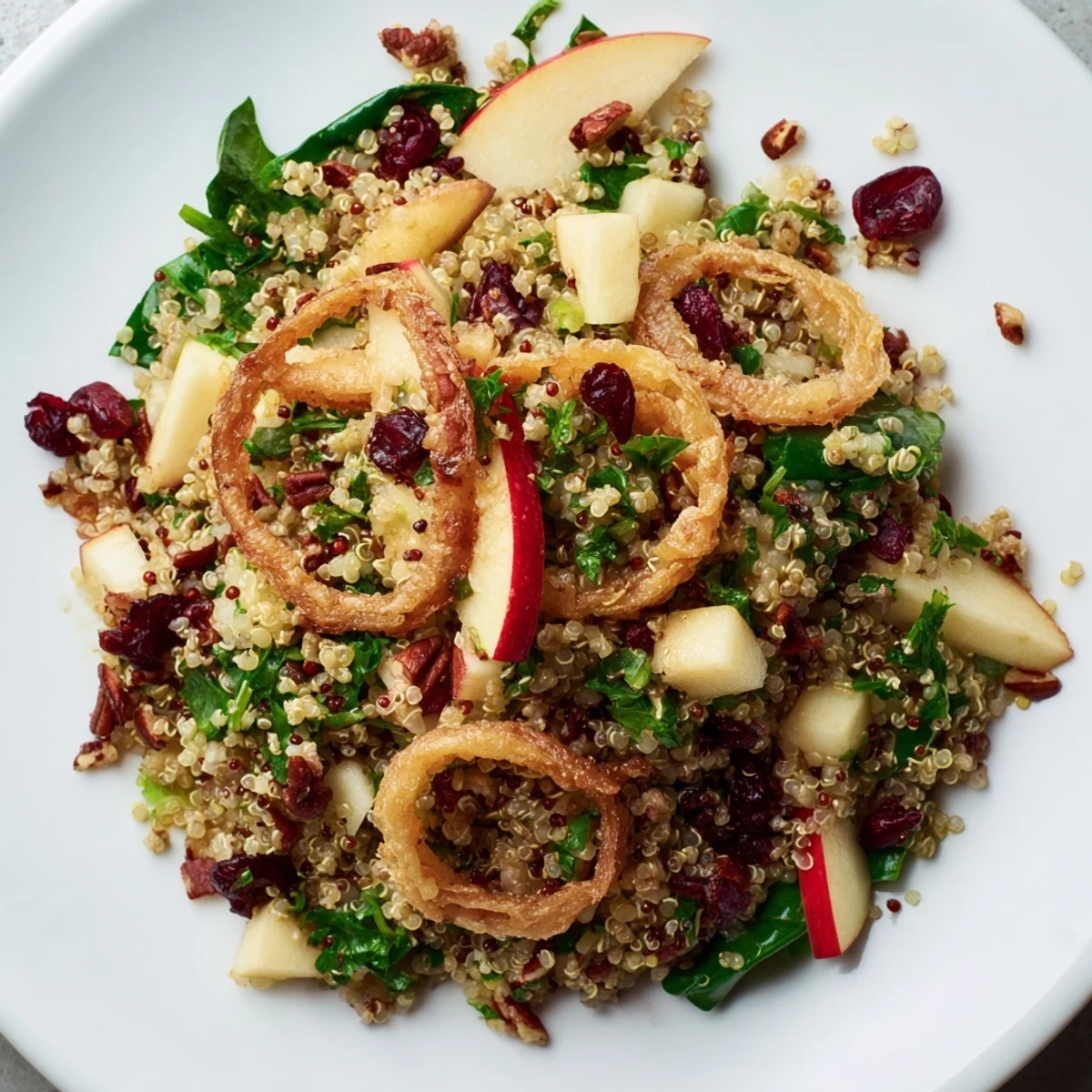 Golden crispy shallots top a colorful honey mustard quinoa apple salad in a wooden bowl