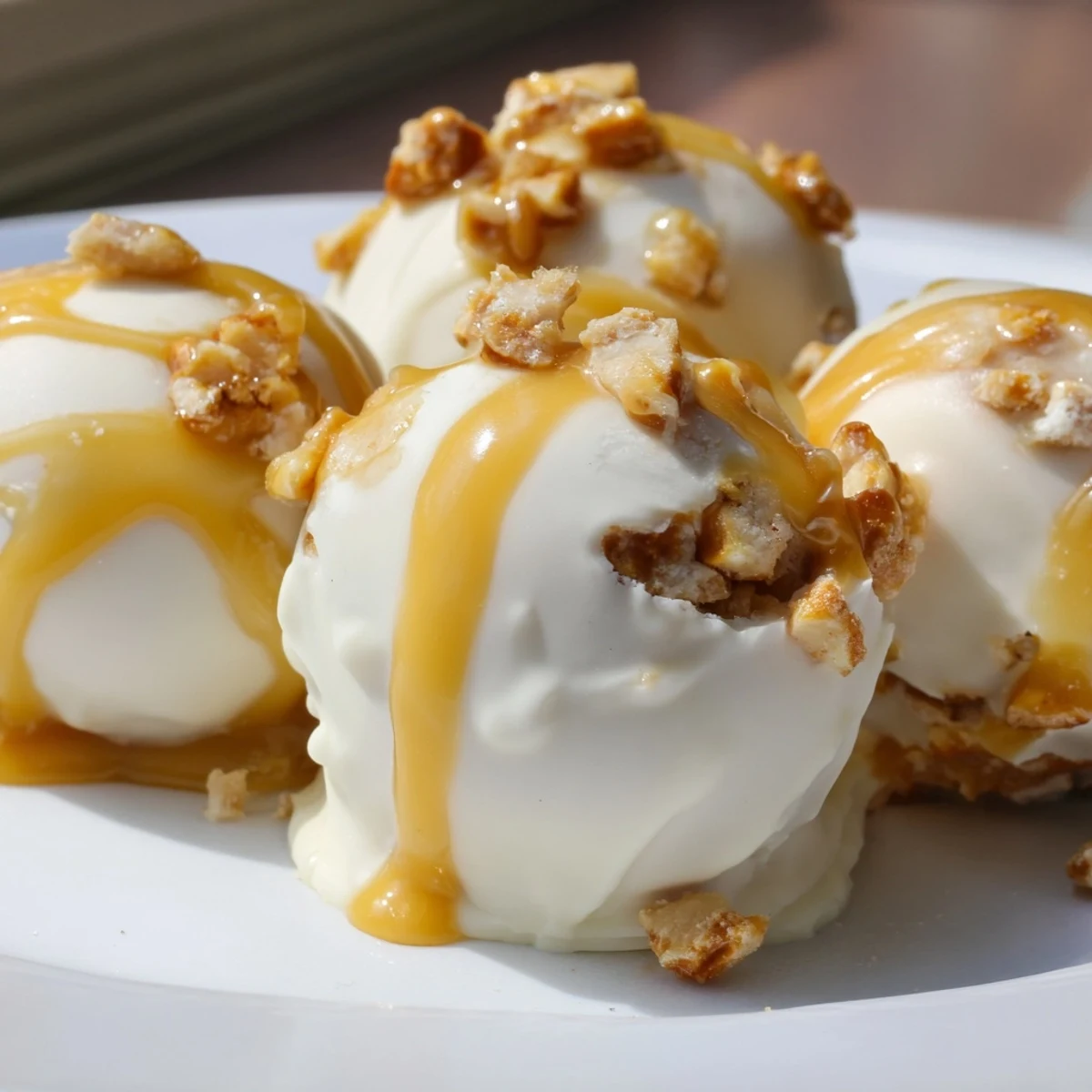 Bite-sized salted caramel pretzel cheesecake balls glistening with white chocolate and sticky caramel drizzle